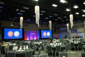 two large projection screens and dining tables for several hundred people